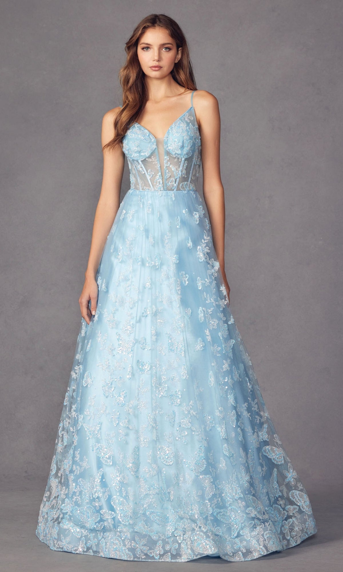 A woman wearing the Sheer-Corset Glitter-Print Long Prom Dress 2413, featuring a long A-line silhouette and sheer bodice, poses against a plain gray background.